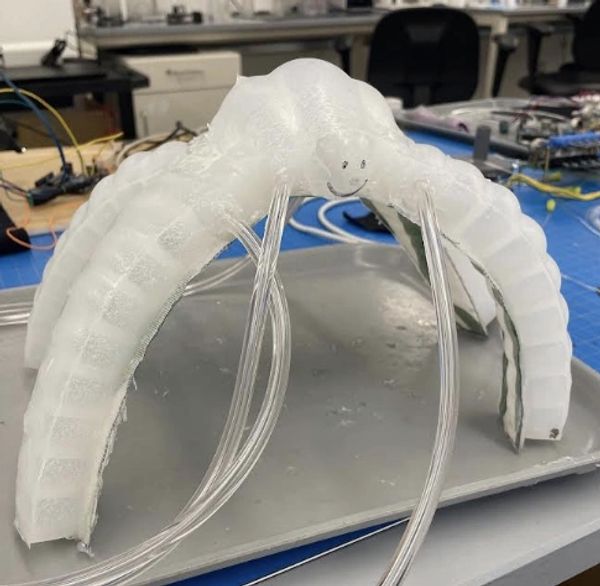 A translucent robotic octopus with tubes, placed on a metallic tray in a lab environment.