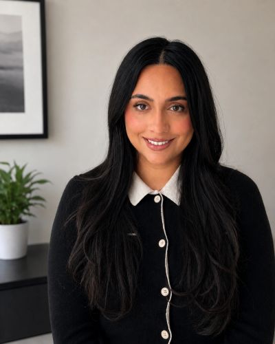 Smiling woman with long black hair wearing a black cardigan.