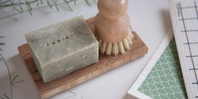 A natural soap bar and wooden brush on a wooden tray.
