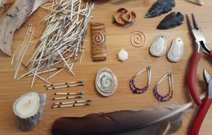 A collection of handmade jewelry and crafting tools on a wooden surface.