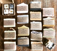 Variety of handcrafted soaps and bath items arranged on a wooden surface.