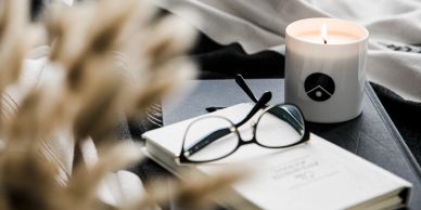 Cozy setup with a lit candle, glasses, and an open notebook.
