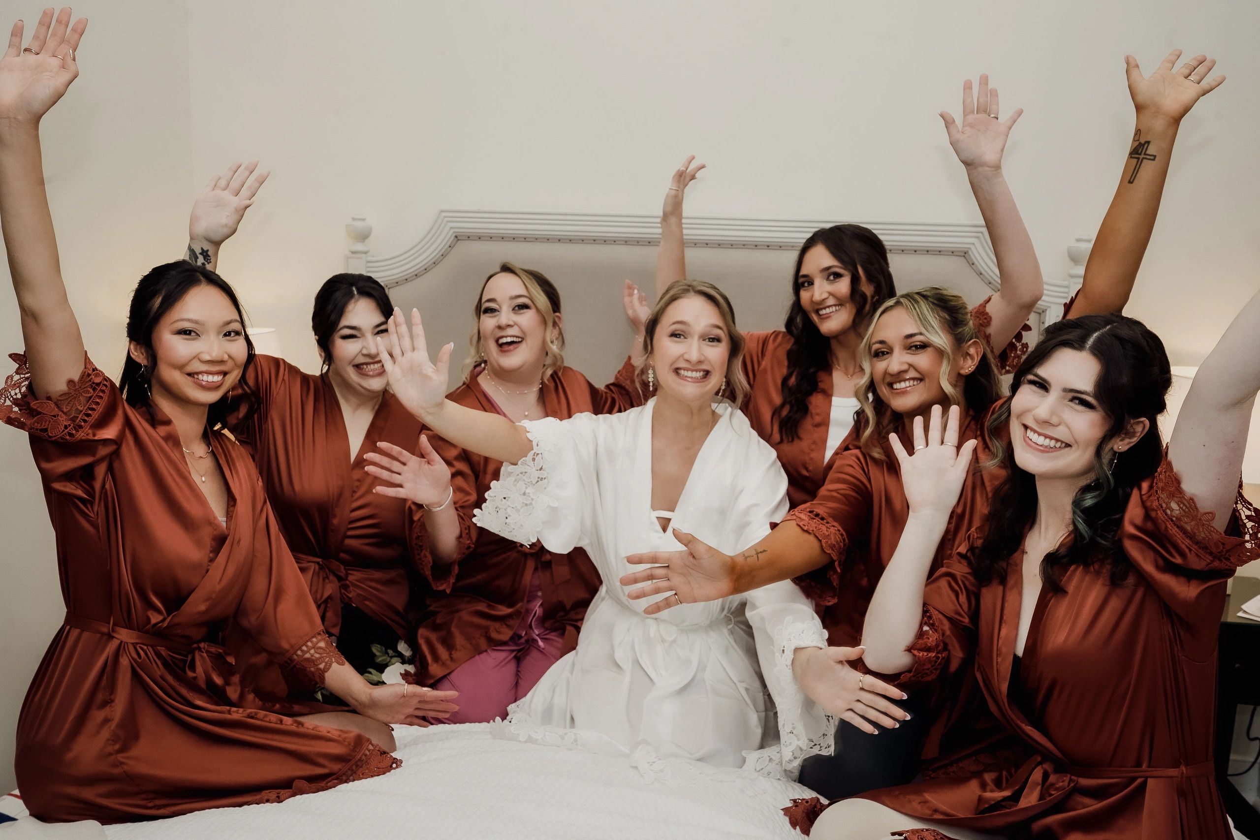 Bridesmaids and bride happily waving their hands.