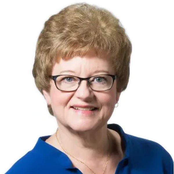 Smiling woman with glasses and curly hair.