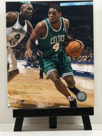 Basketball player in Celtics jersey dribbling against defender.