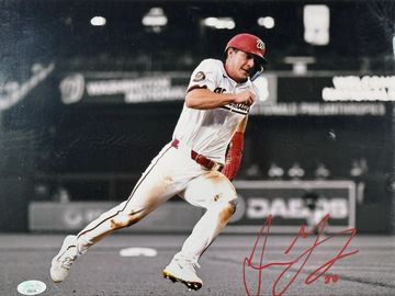 Baseball player running during a game, wearing a white uniform and red helmet.