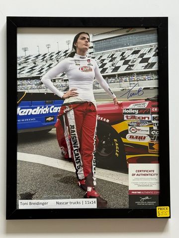 Toni Breidinger standing beside a Nascar truck at a race track.