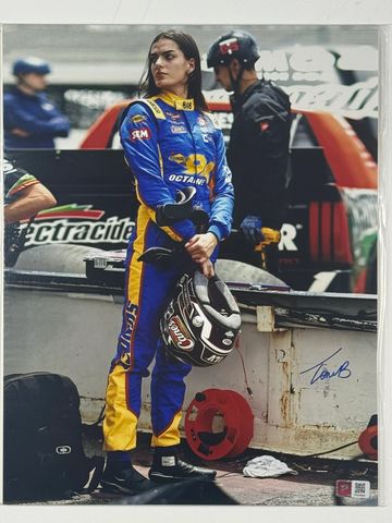 Female racecar driver holding a helmet, standing near a race car.