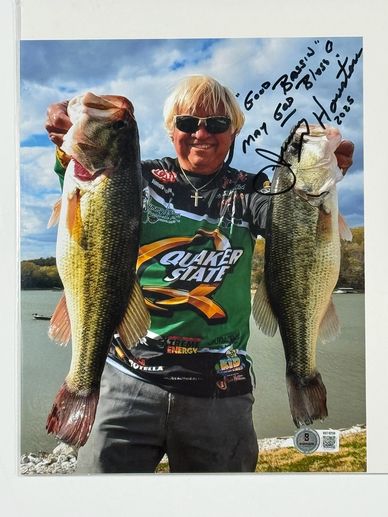 Man holding two large fish near a lake.
