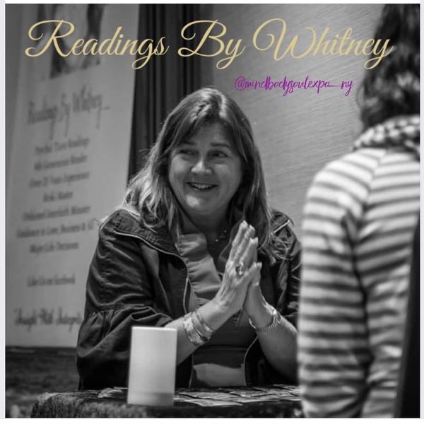 Whitney offers readings with a warm smile at a table.