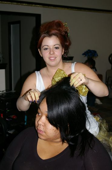 A smiling Beautician at Unique Impressions Salon, styling a client's hair after color application.
