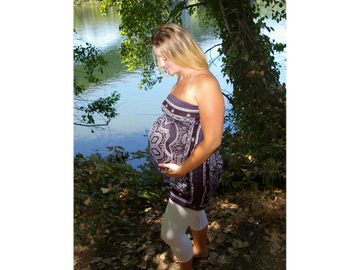 Mother holding her belly from her pregnancy on the shore of the colorful river scene.