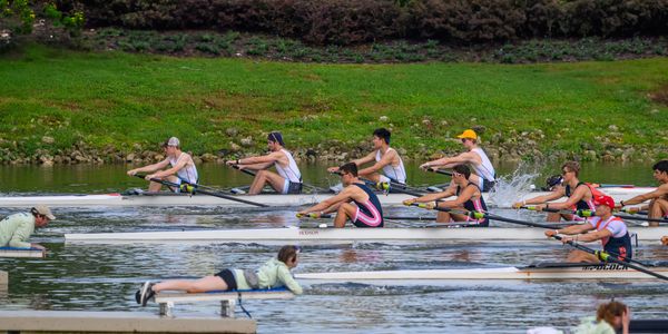 Rowing teams racing on a river with coaches observing.