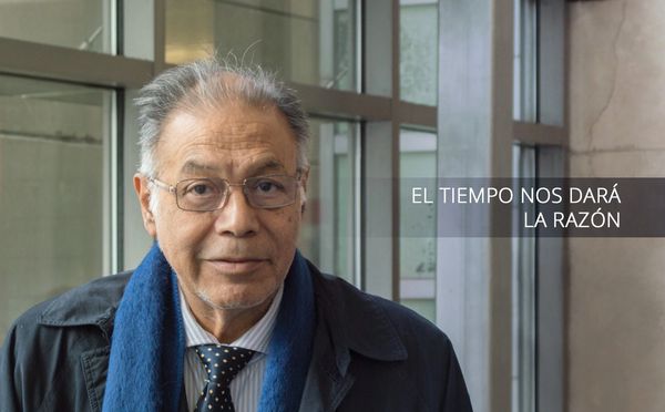 An elderly man with glasses and a blue scarf stands indoors, with a quote beside him.
