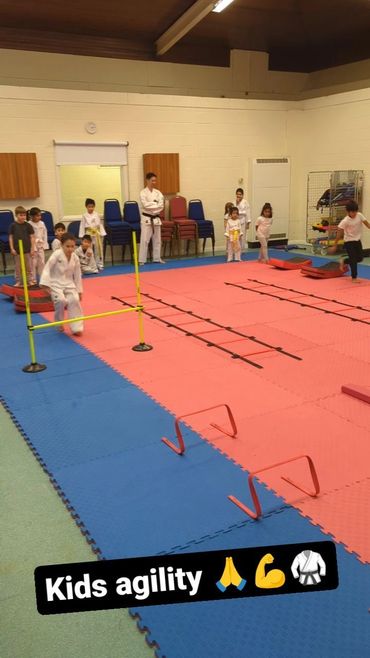 Children practicing agility drills in a martial arts class.