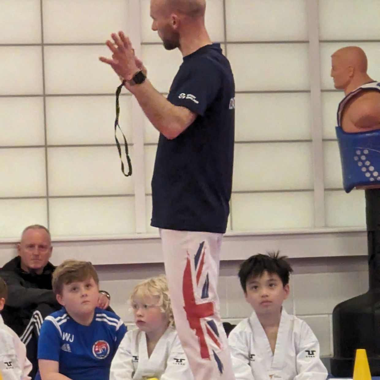 Martial arts instructor teaching young students in a dojo.