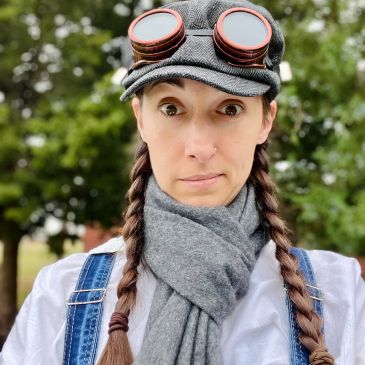 Person with braided hair and goggles on cap outdoors.
