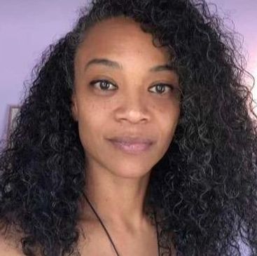Woman with curly hair looking at the camera.