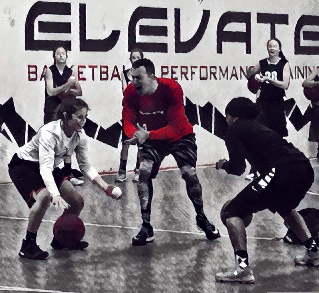 Basketball players training intensely in a gym with a coach.