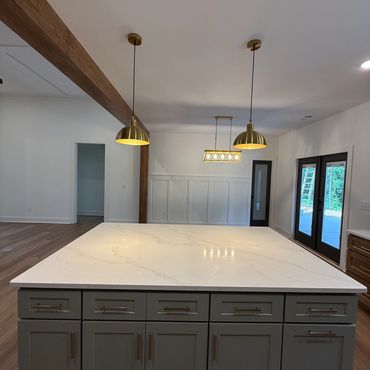 Modern kitchen island with marble countertop and gold pendant lights.