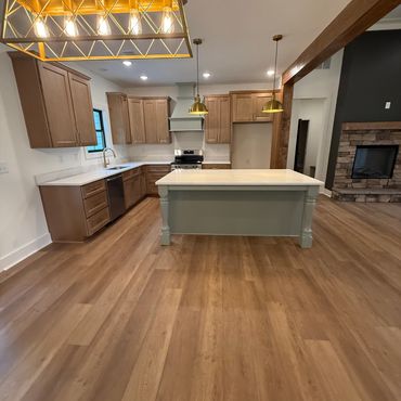 Modern kitchen with wooden floors, island, and pendant lights.