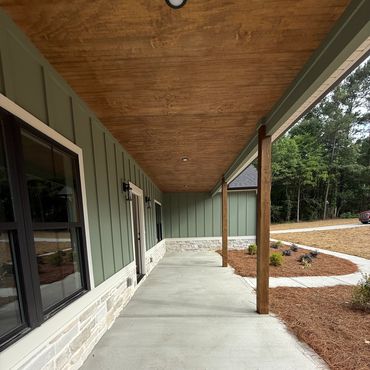 Spacious front porch with wooden ceiling and green siding.