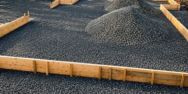 Wooden frames filled with gravel for construction groundwork.