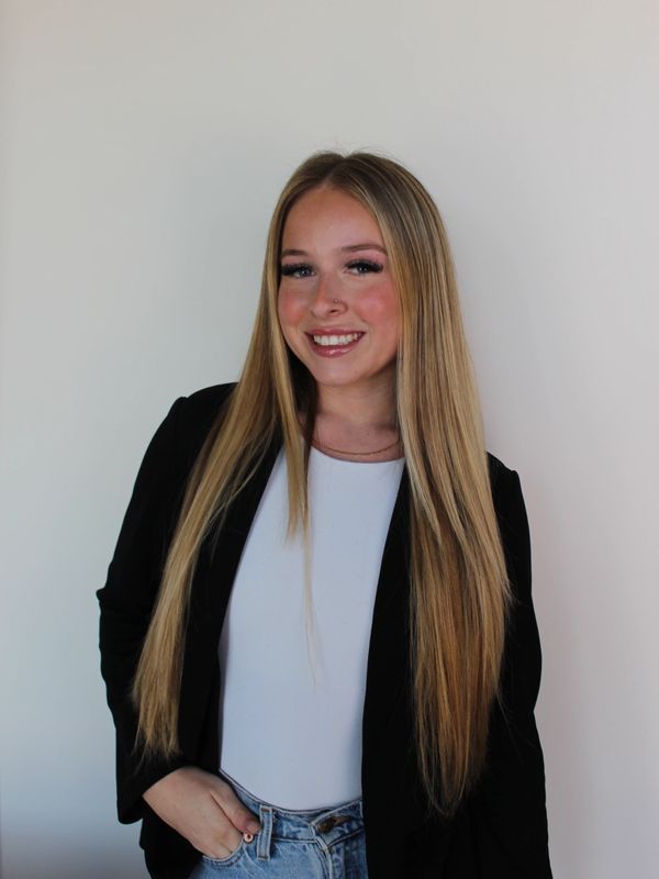 Smiling young woman with long blonde hair in casual chic outfit.