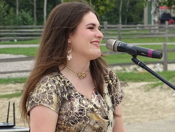 Woman singing and playing guitar outdoors.