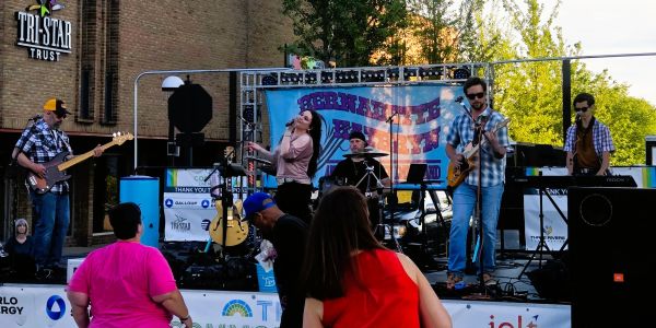 Band performing live on outdoor stage with audience.