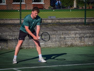 Man preparing to hit a tennis ball on an outdoor court.