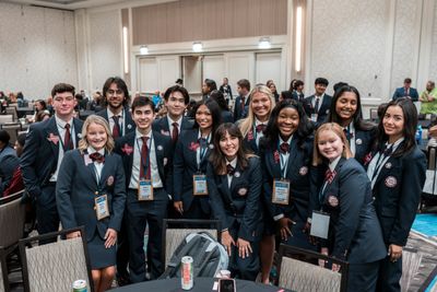 A group of young people in formal attire posing for a photo indoors.
