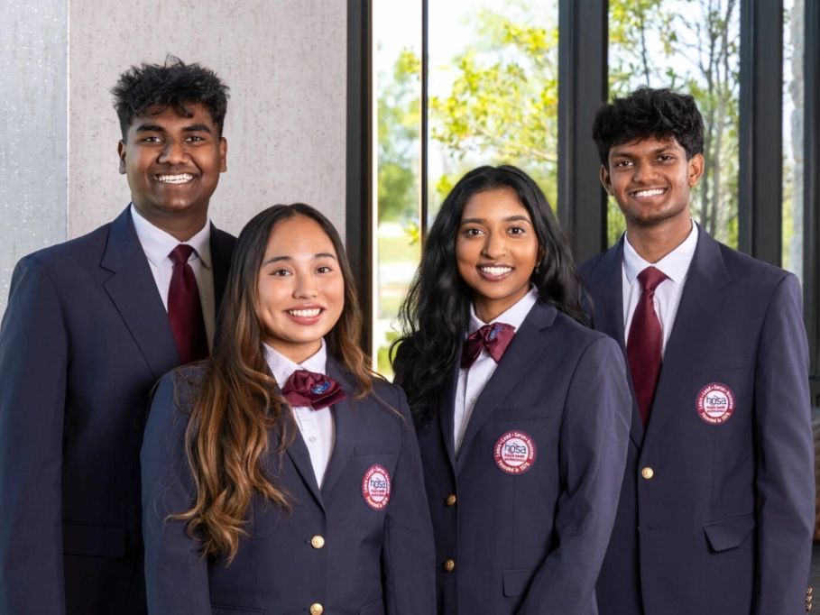 Four young people in formal attire smiling.