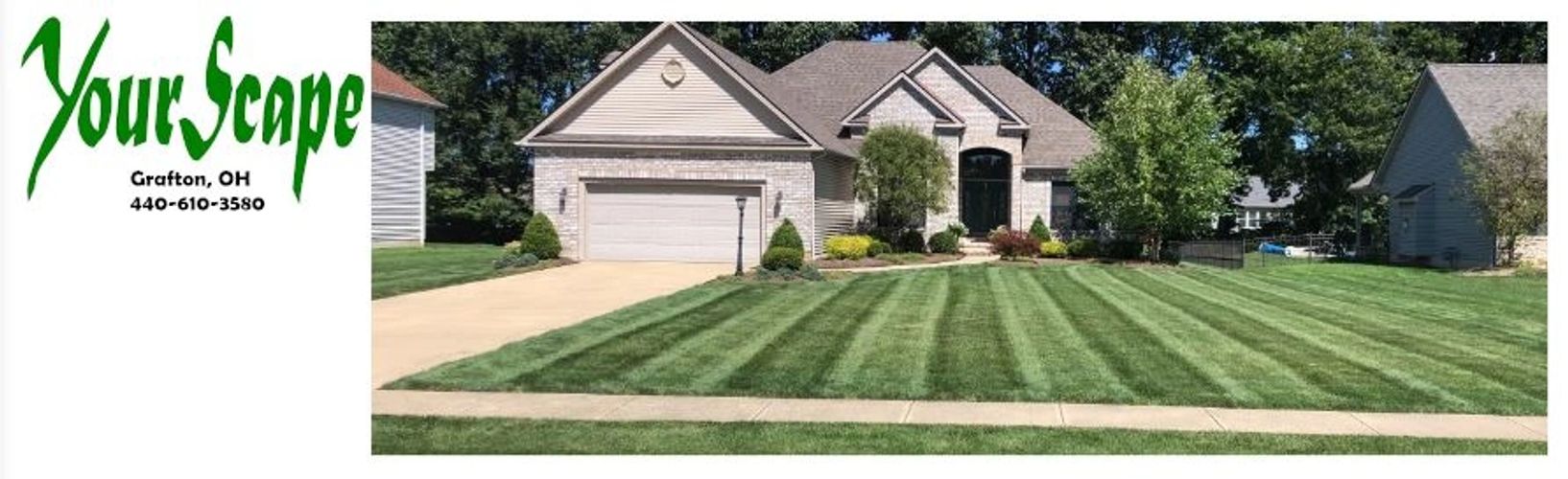 Well-maintained house with striped lawn and landscaping.