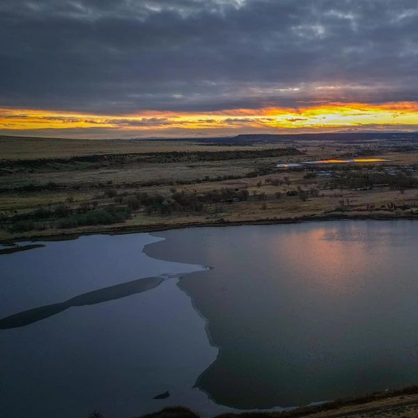 Sunset over a calm lake with a dramatic cloudy sky.