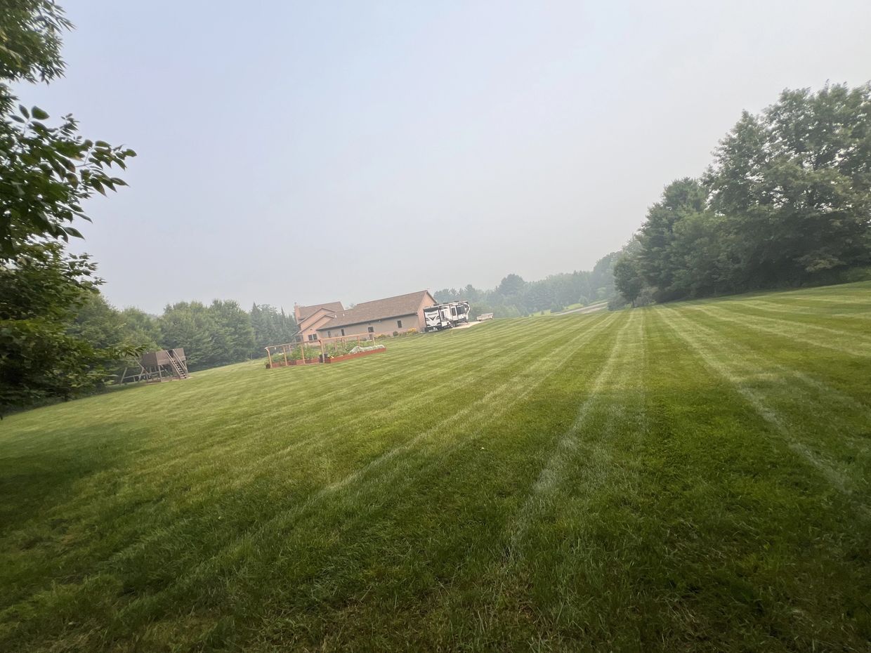 Large grassy field with a house and RV.