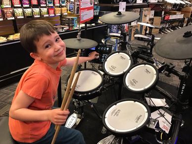 A grandson trying out a drum set at a music store