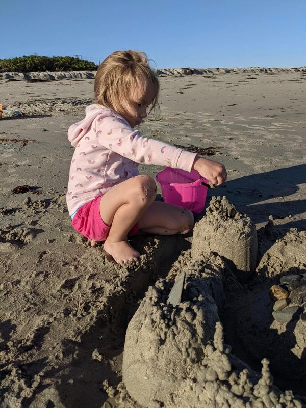 Granddaughter dripping sand onto a sand castle