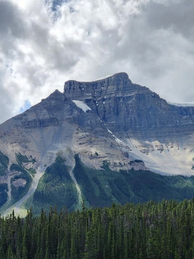 Rugged peak in the Canadian Rockies, with a fortress-shaped rock formation at the top