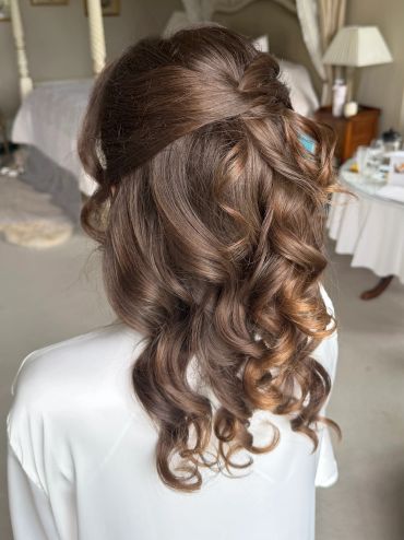 Elegant half-up curly hairstyle with soft waves.