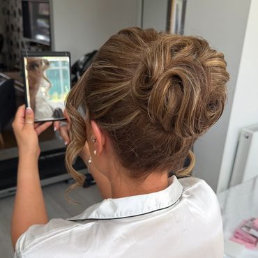 Woman with elegant updo hairstyle looking at a photo on her phone.