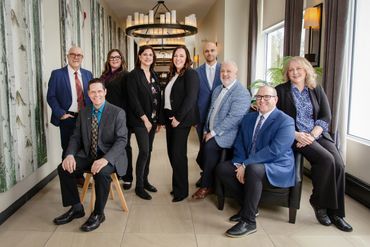 Professional group portrait of nine business people in a modern office setting.