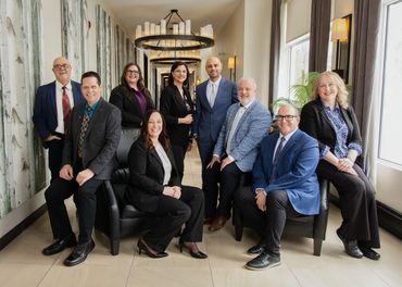 A professional group of nine people posing in a hallway.