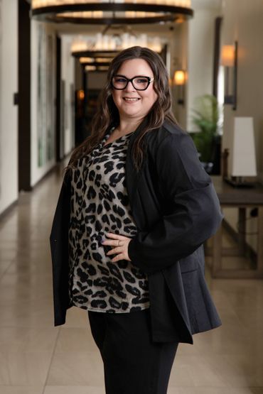 Woman in glasses and leopard print top smiling indoors.