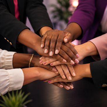 Diverse hands stacked together in a teamwork gesture.