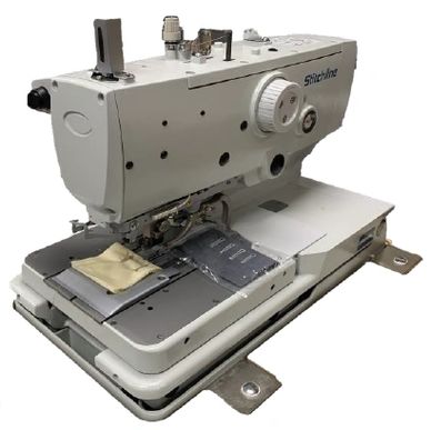 A white industrial sewing machine with fabric pieces under the needle.