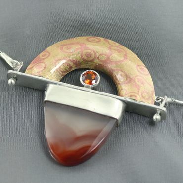This 20" mokume gane necklace features an agate tongue sterling chain and spessartine garnet