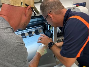 Two men working on a printer or similar machine.