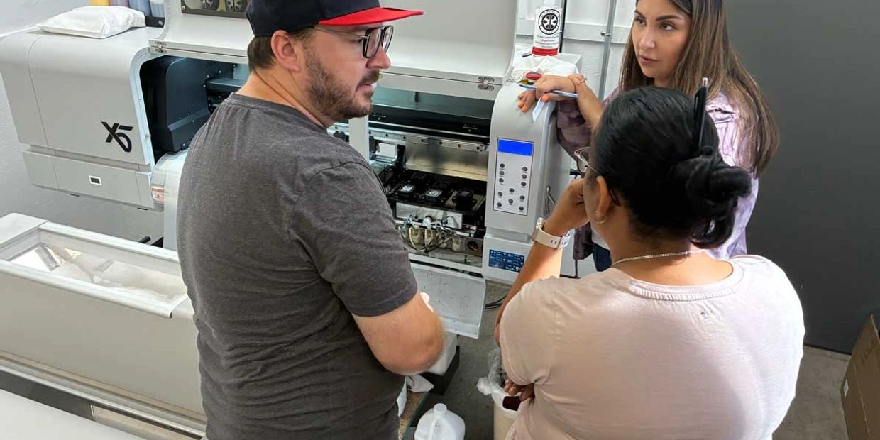 Three people discussing near an open machine.