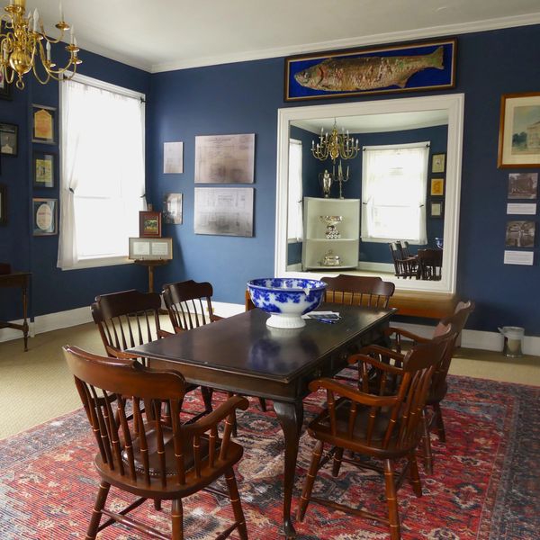 A classic dining room with wooden chairs and blue walls.